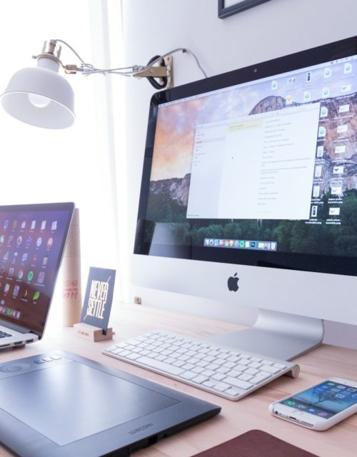 silver iMac near iPhone on brown wooden table